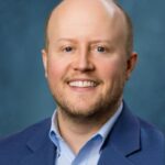 Bald smiling man in his forties in a suit.