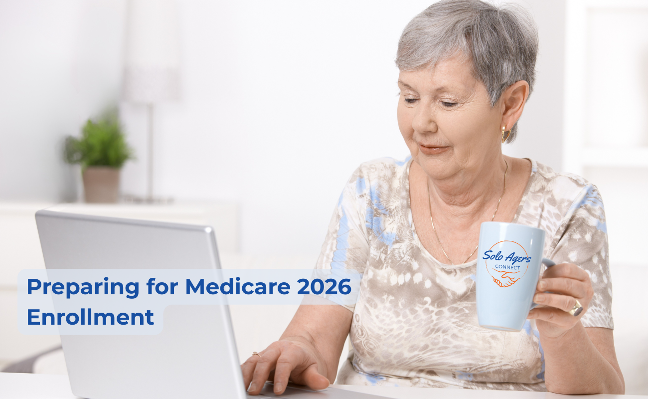 An older woman with short gray hair sits at a desk using a laptop while holding a light blue mug that says “Solo Agers Connect.” She appears focused and content in a bright, comfortable room. Text on the image reads, “Preparing for Medicare 2026 Enrollment.”