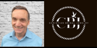 A photo of Gemologist Dan Balboni smiling next to a large logo of his business Christian Bridal Jewelry.