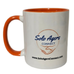Solo Agers coffee cup A white coffee mug with and orange colored handle and inside with the SoloAgersConnect.com logo and website address prrinted on the front.